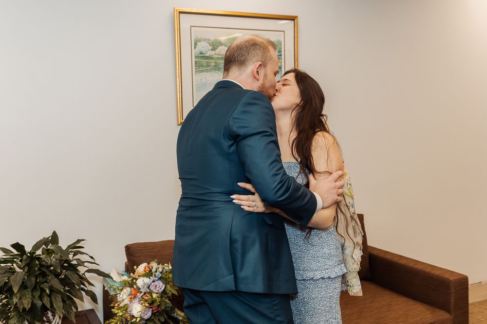 Couple sharing a first kiss during intimate wedding ceremony indoors.