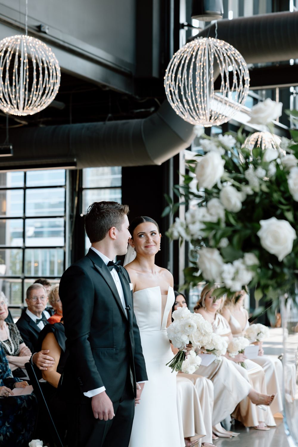 Bride and groom share a tender moment at the altar during their elegant indoor wedding ceremony.