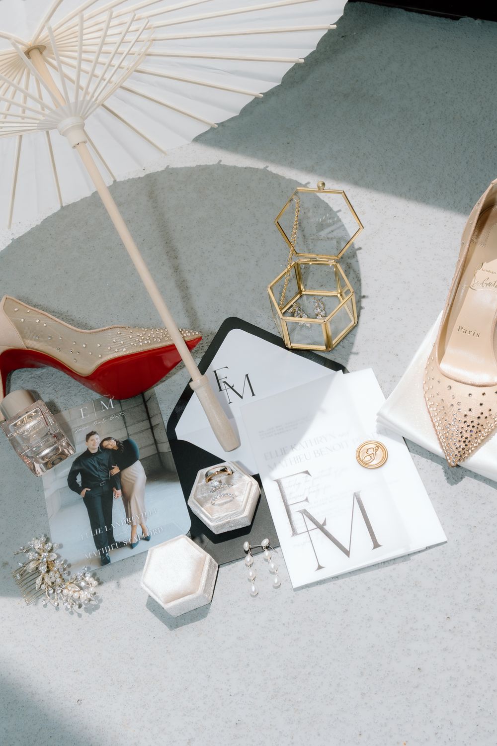 Elegant wedding flat lay with Christian Louboutin heels, rings, invitations, and gold decor.