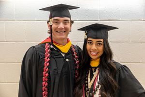 Graduates in black caps and gowns pose together at a commencement ceremony.