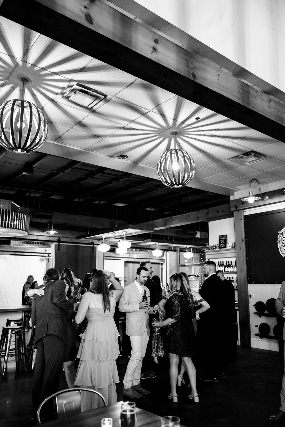 Black and white panorama of a wedding reception venue with decorative lanterns and guests mingling on the dance floor.