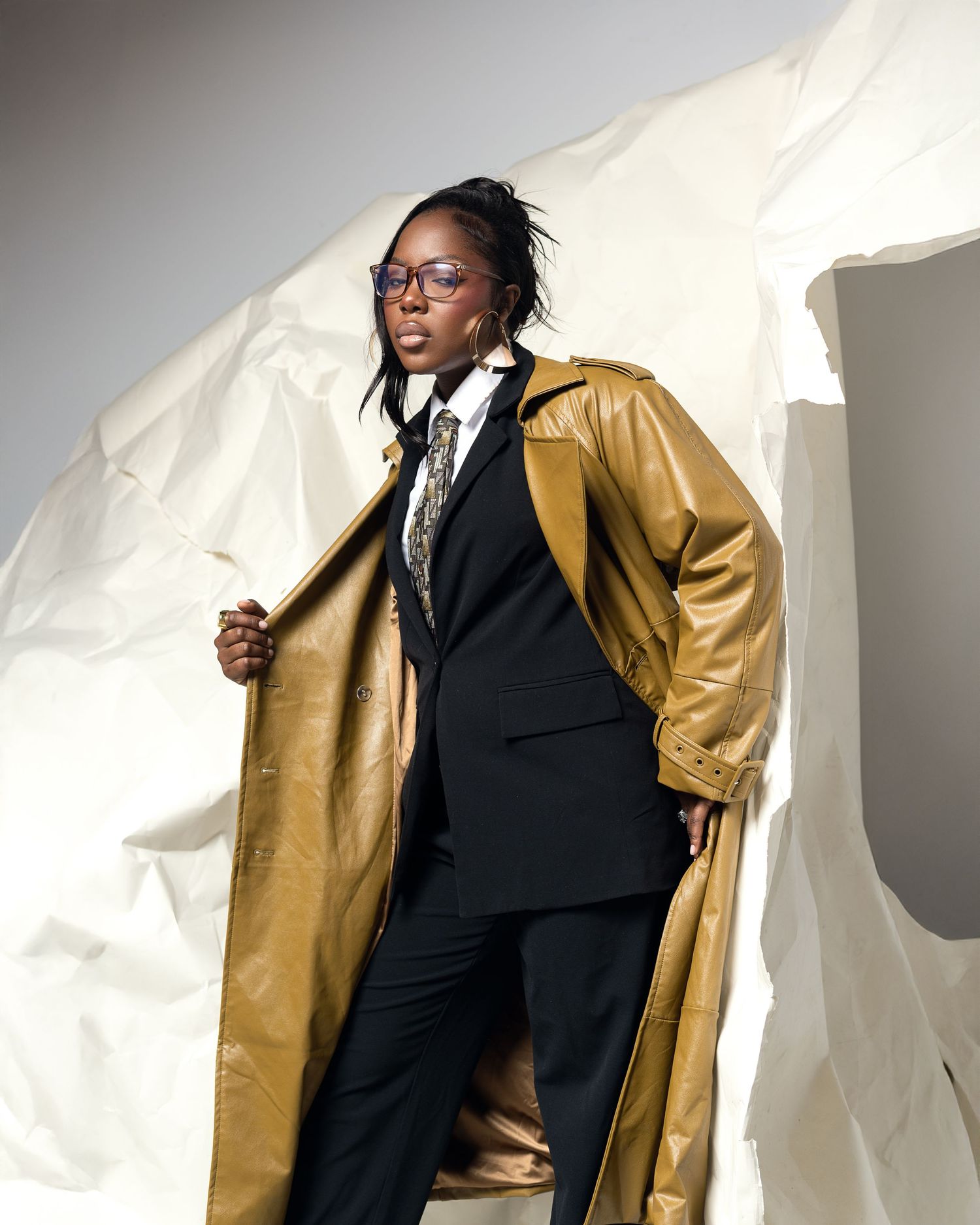 Fashion portrait against beige background showing model in luxurious brown faux fur coat with off-shoulder styling.