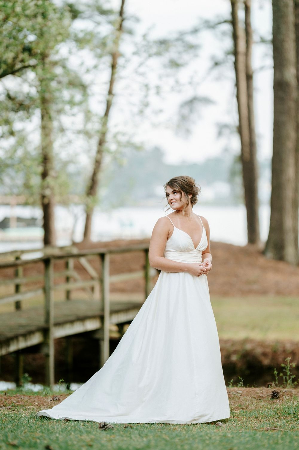 White wedding gown captured in a series of romantic poses on a wooden walkway amidst natural scenery.