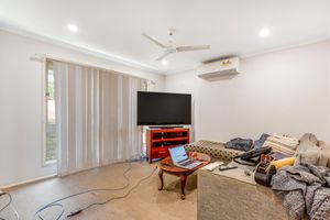 Casual living room with large TV, ceiling fan, split system air conditioner, and sheer curtain sliding doors.