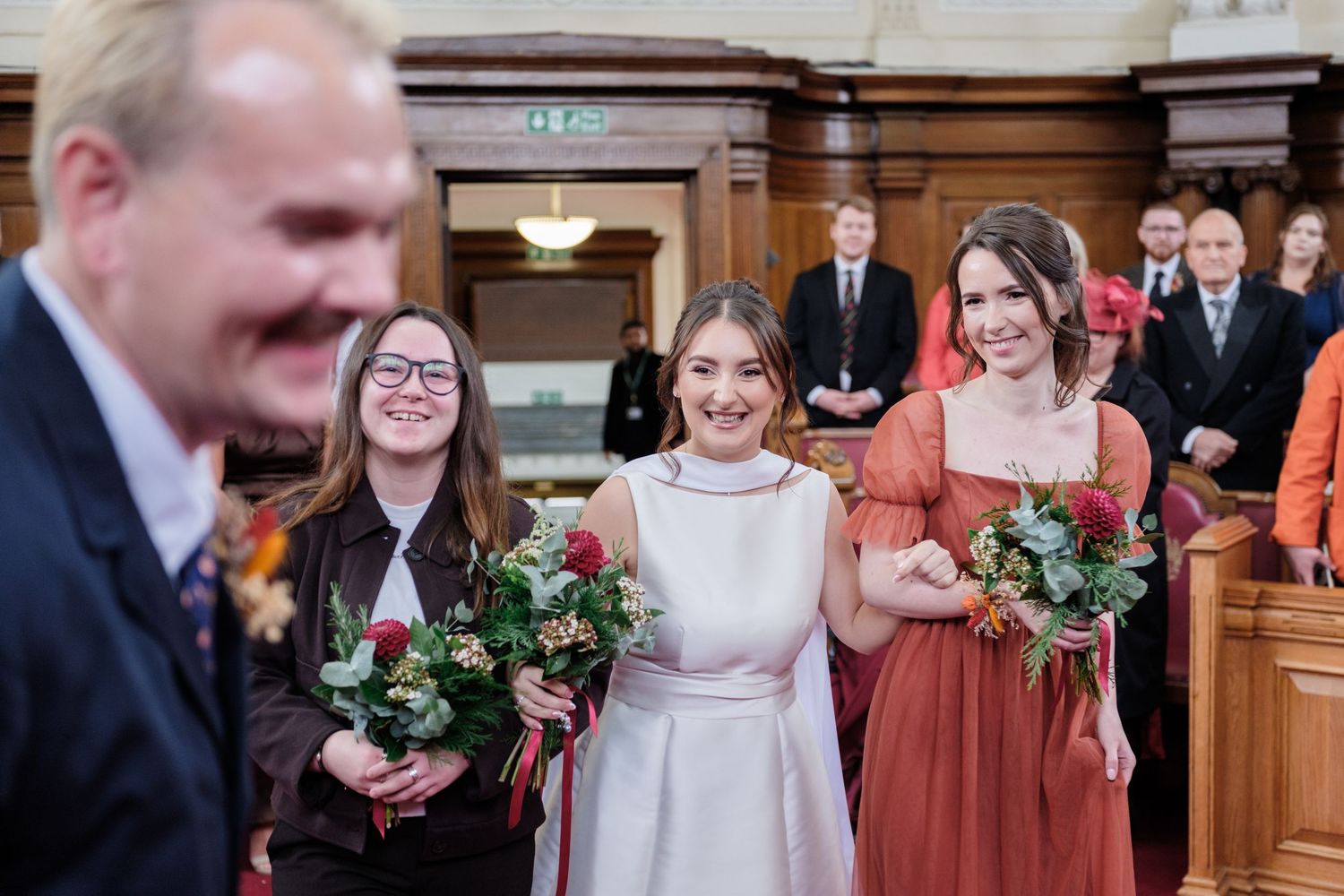 A bride and her bridesmaids stand together in a formal wedding setting.