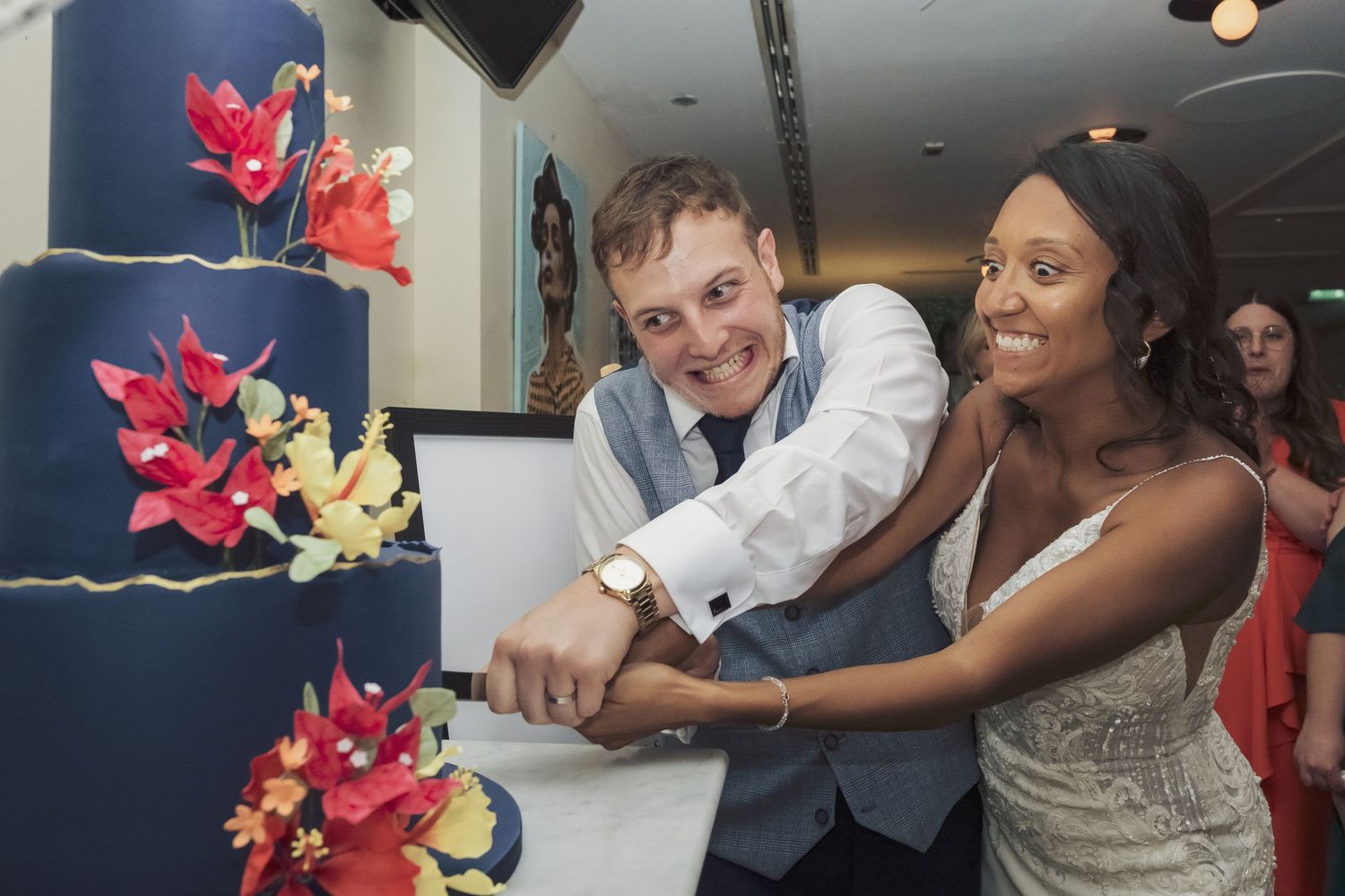 A man and a woman cutting a large wedding cake together at an event.