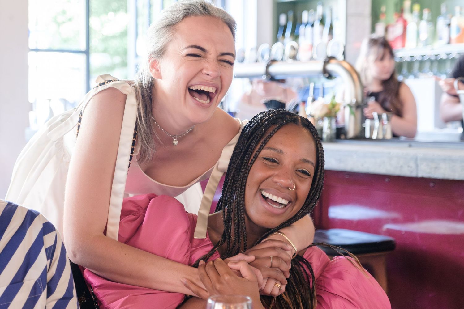 Two young women laughing and smiling together in a cafe.