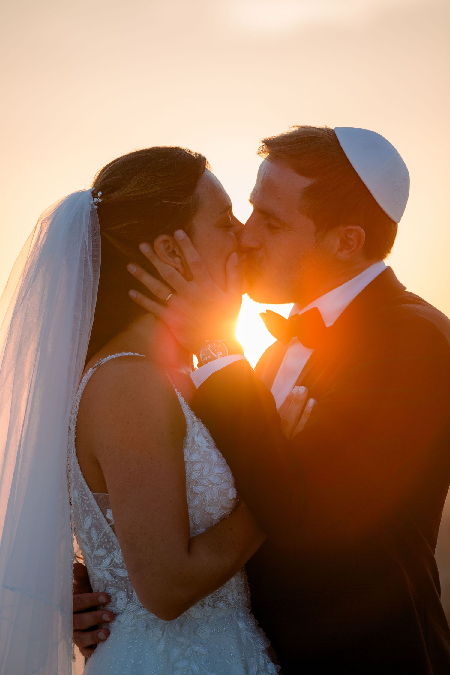 Silhouetted couple in wedding attire share romantic kisses at sunset in a series of four connected photos.