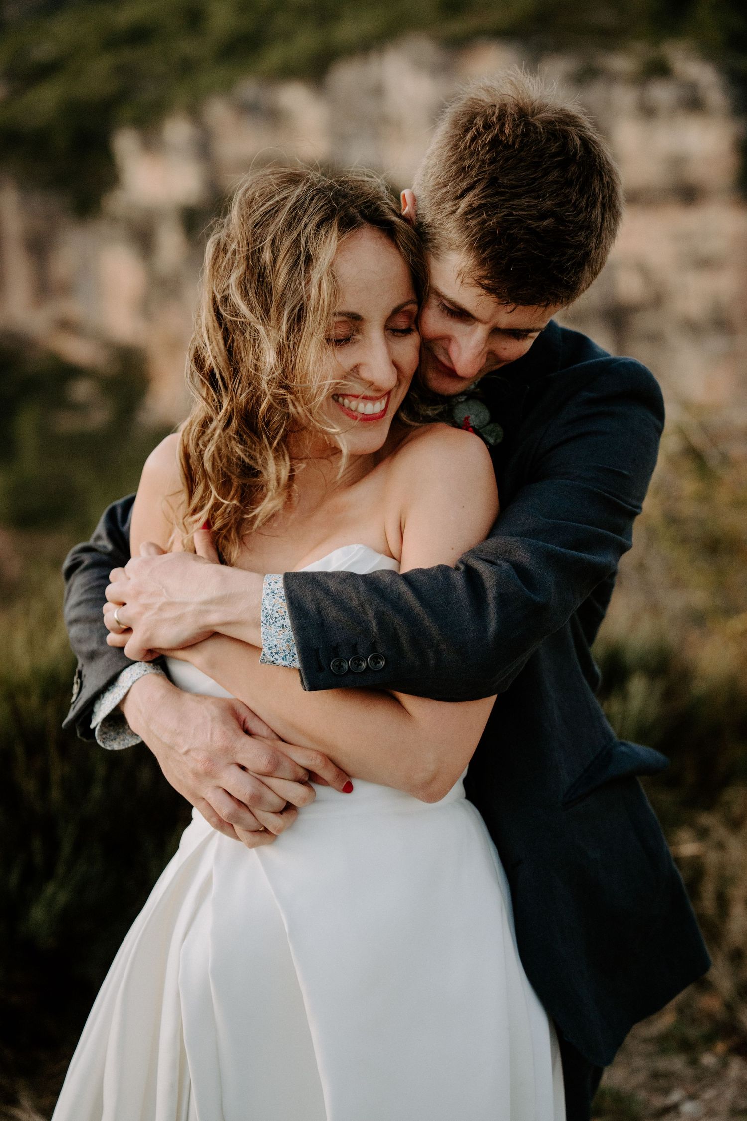 Tender moments shared between couple in formal attire against rocky mountain backdrop.
