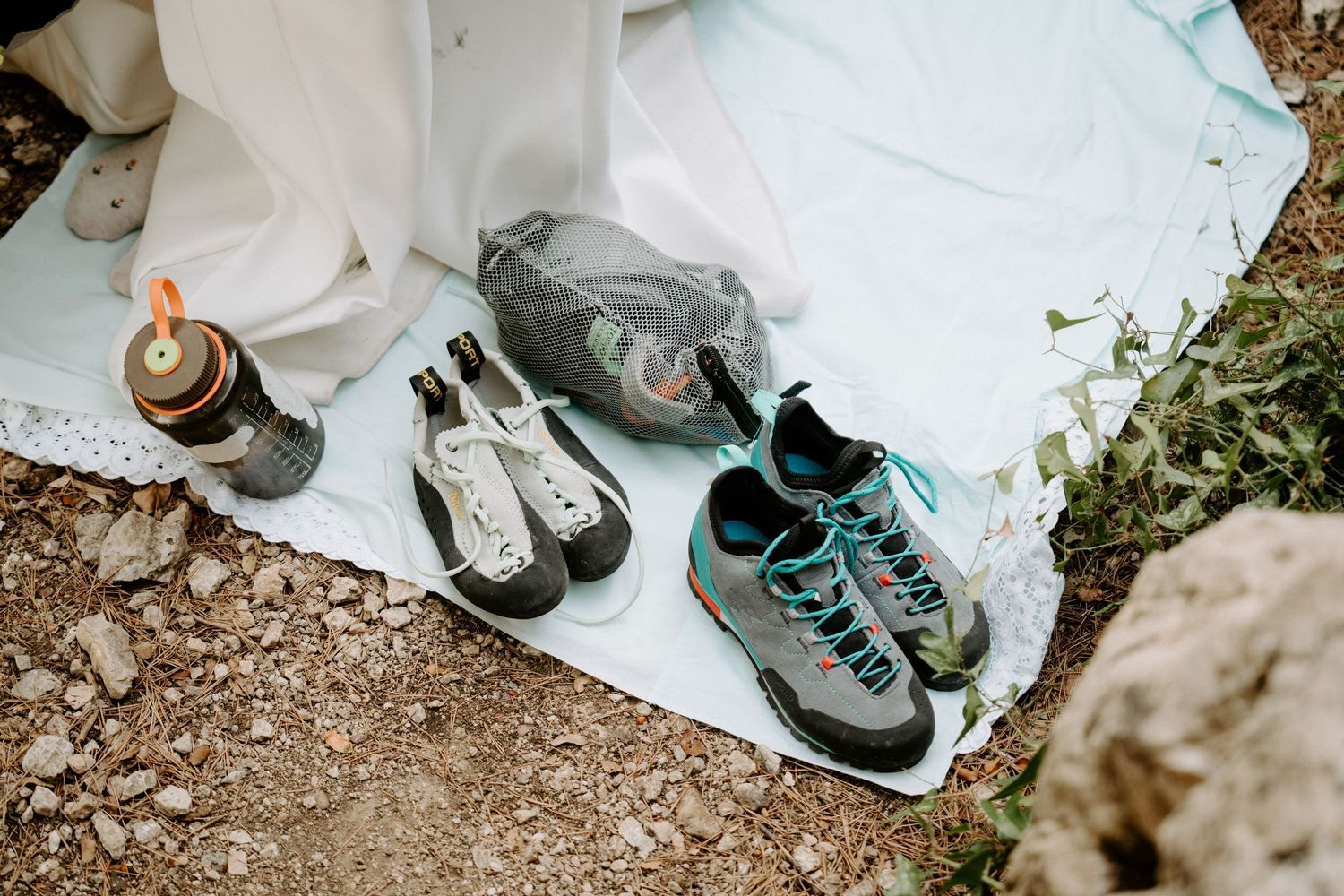 Hiking boots and camping gear laid out on white cloth outdoors during an adventure preparation.