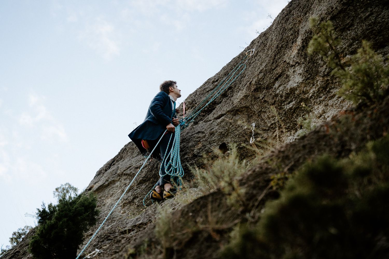Rock climbers ascending a steep cliff face in outdoor adventure sequence.