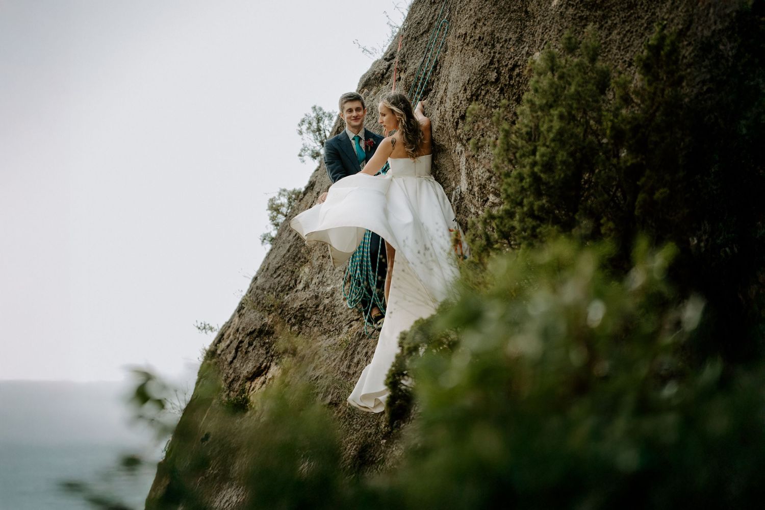 Two figures embrace on a dramatic cliffside overlook against a misty mountain backdrop.