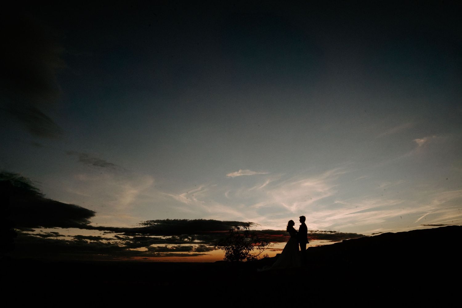 Dramatic sunset silhouettes against a dark mountain landscape.