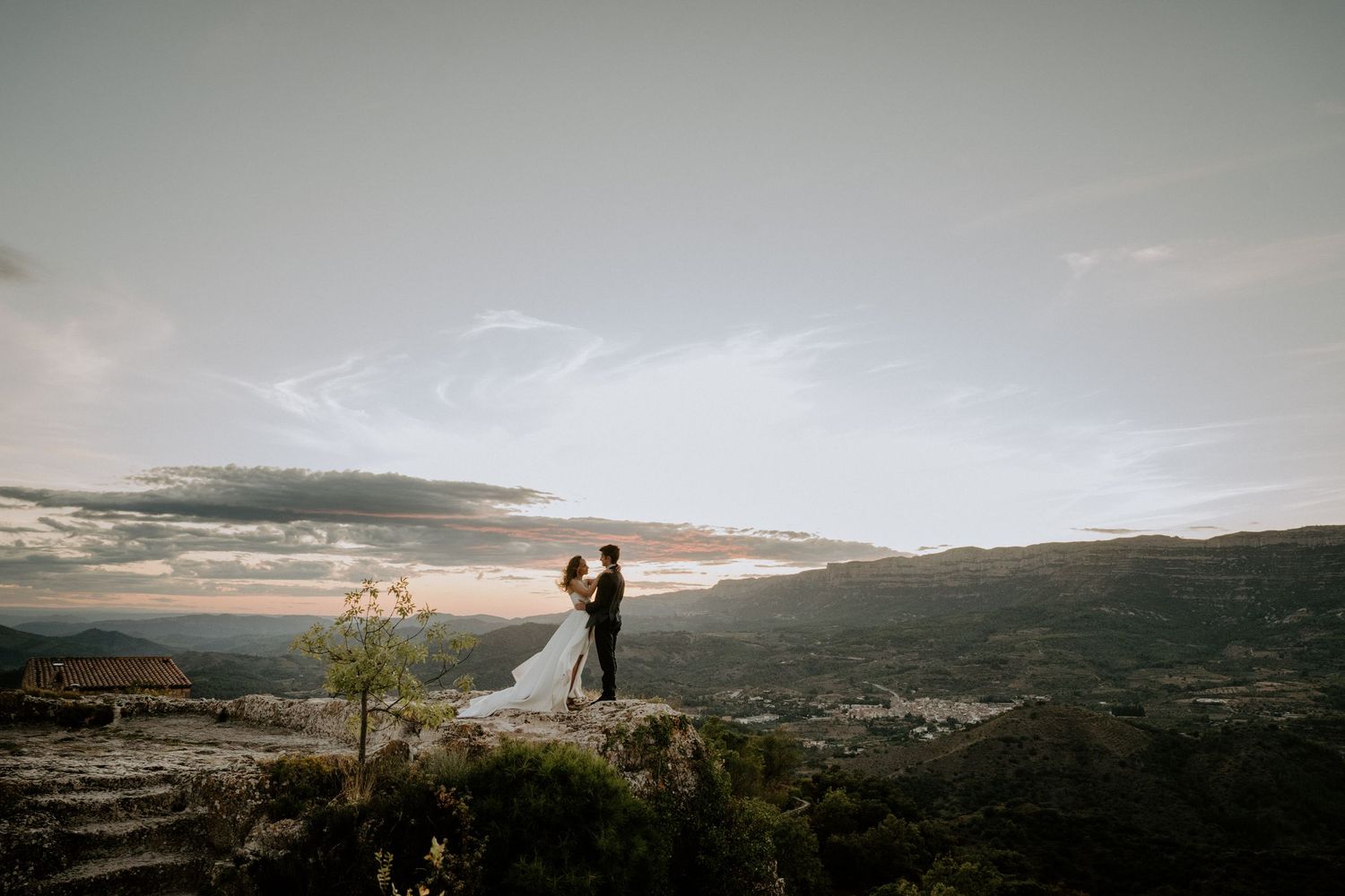 Panoramic mountain landscape at sunset with silhouetted figures overlooking a scenic valley.