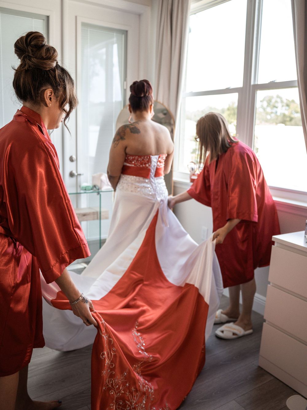 A row of figures wearing red robes and white shawls stand by windows in a bright interior space.