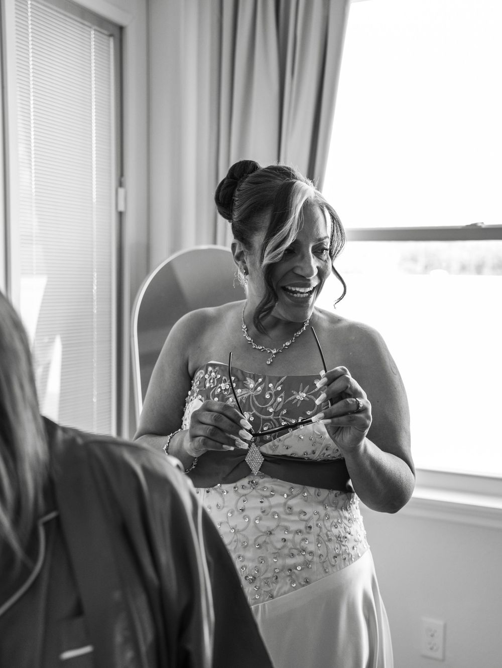 A sequence of black and white photos showing a person getting dressed and laughing in a bridal gown.