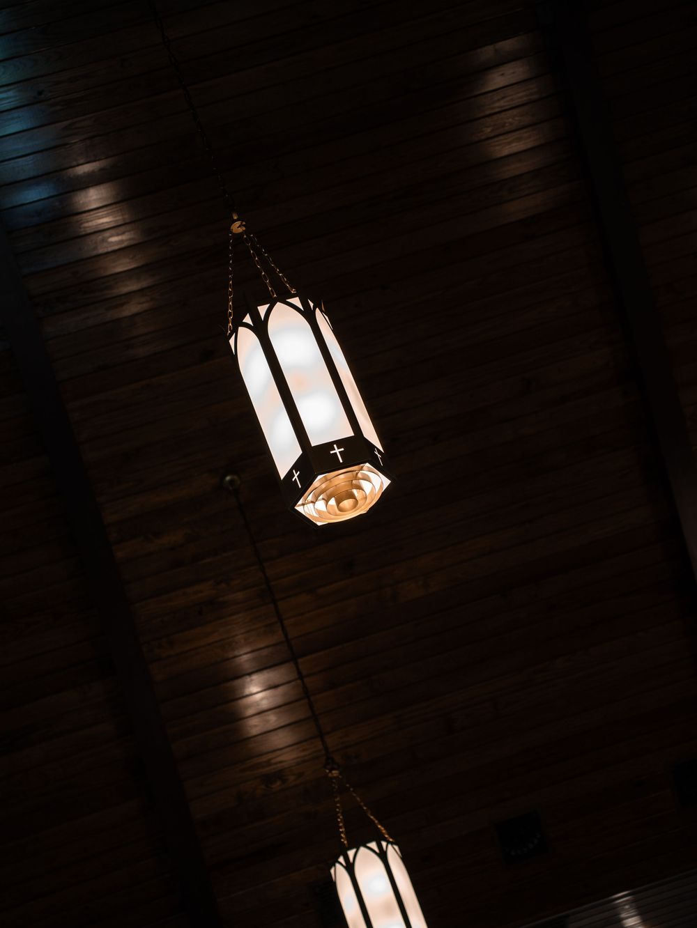 Pendant light fixtures casting dramatic shadows against a dark ceiling in low-light conditions.