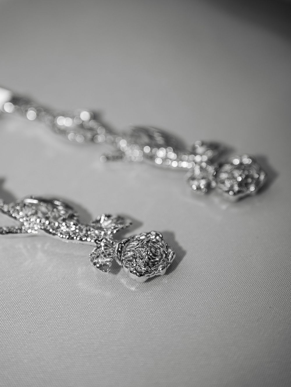 Delicate silver jewelry pieces with intricate filigree patterns arranged on a light gray surface with shallow depth of field.