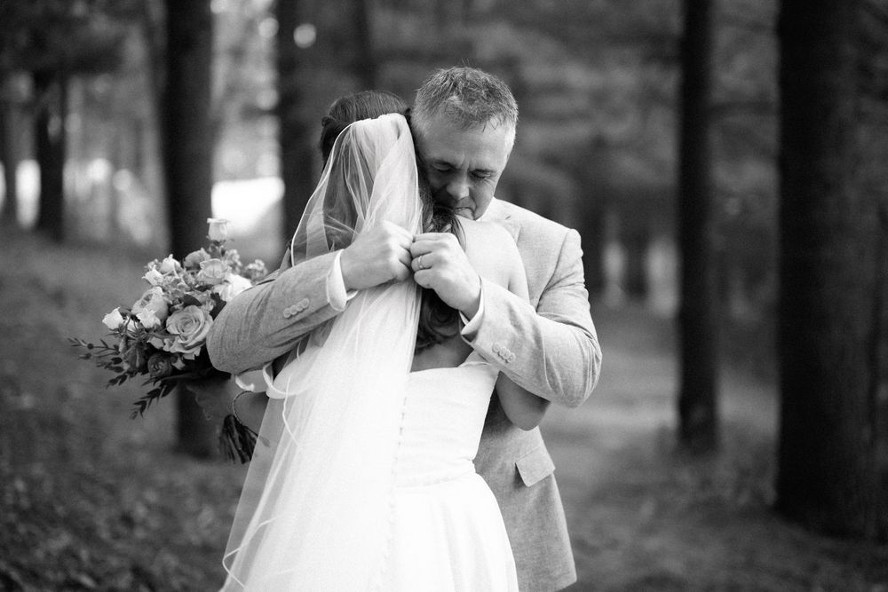 A bride in a white wedding dress walks through a forest setting during a photo session.