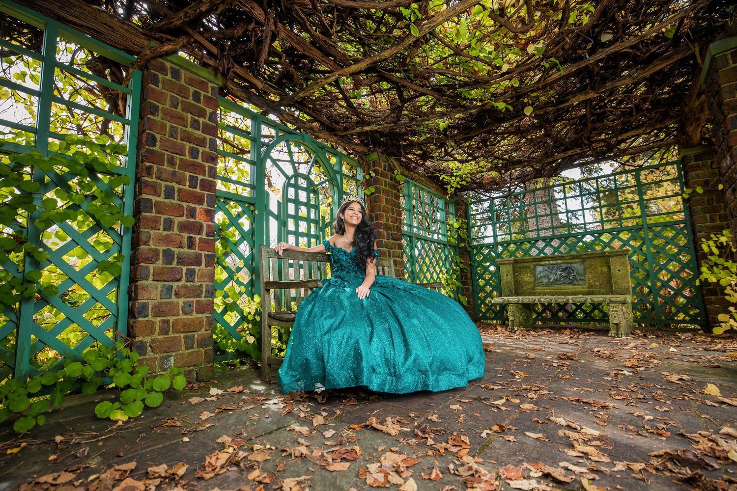 Emerald ball gown photographed in vintage garden pergola with climbing vines.