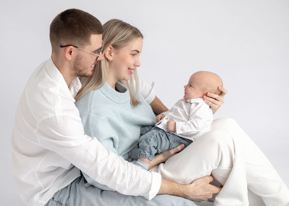 A series of tender family moments captured in soft white and blue tones against a light background.
