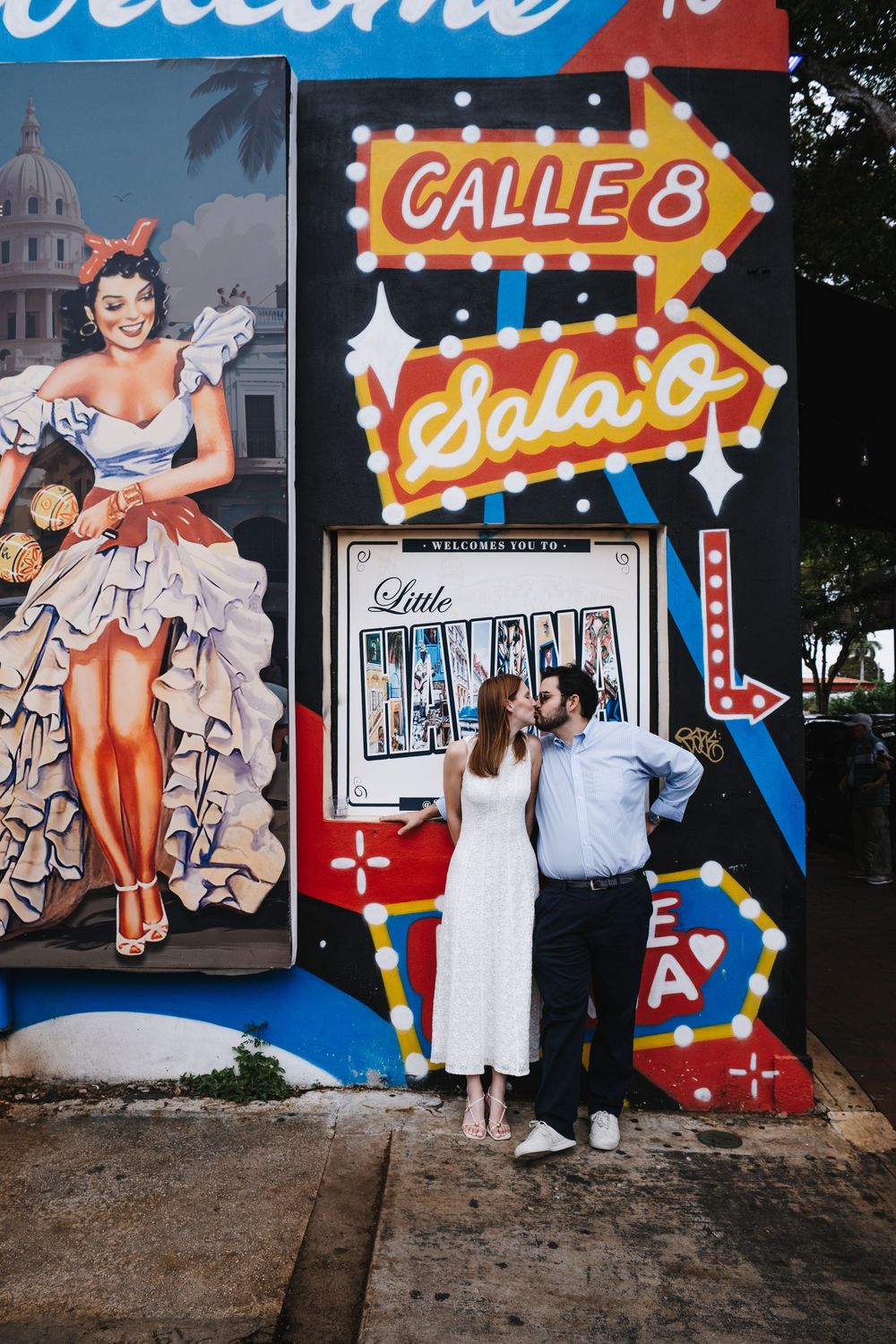 Couple sharing a kiss in front of a colorful Little Havana Calle 8 mural in Miami, Florida.