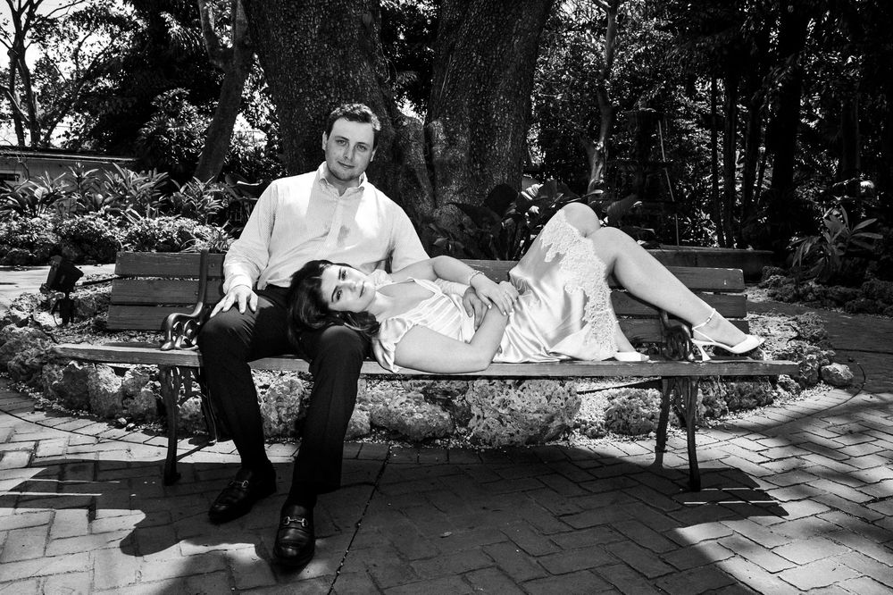 A series of black and white photos showing a couple lounging together in a park setting.