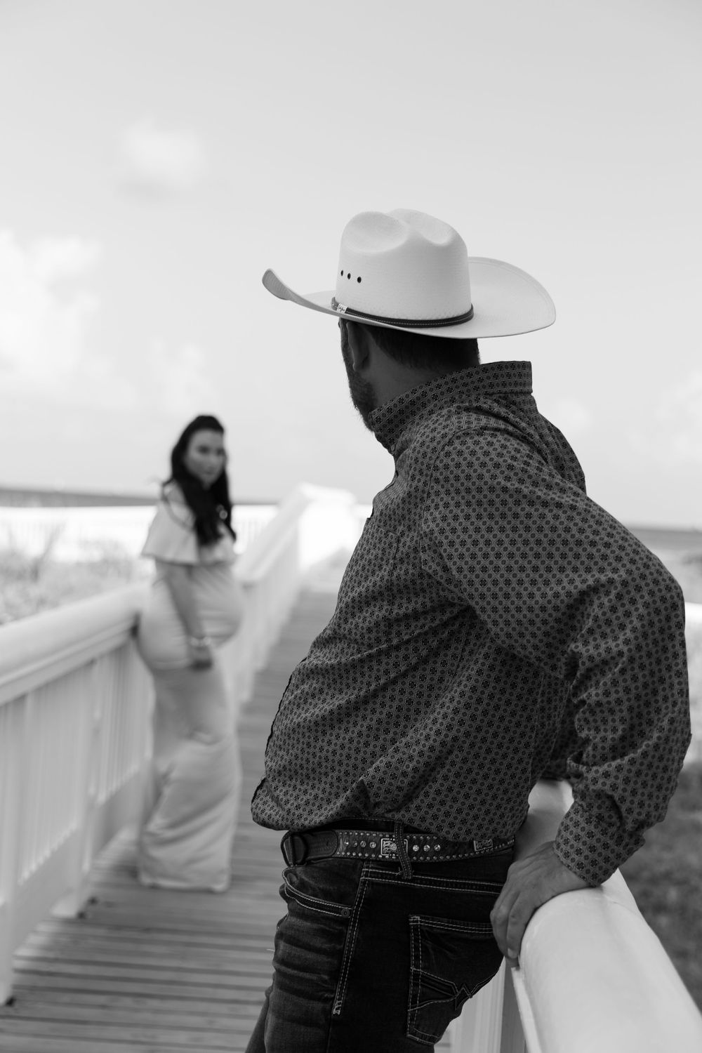 Black and white photo series showing a cowboy and bride on a boardwalk in a romantic photoshoot moment.