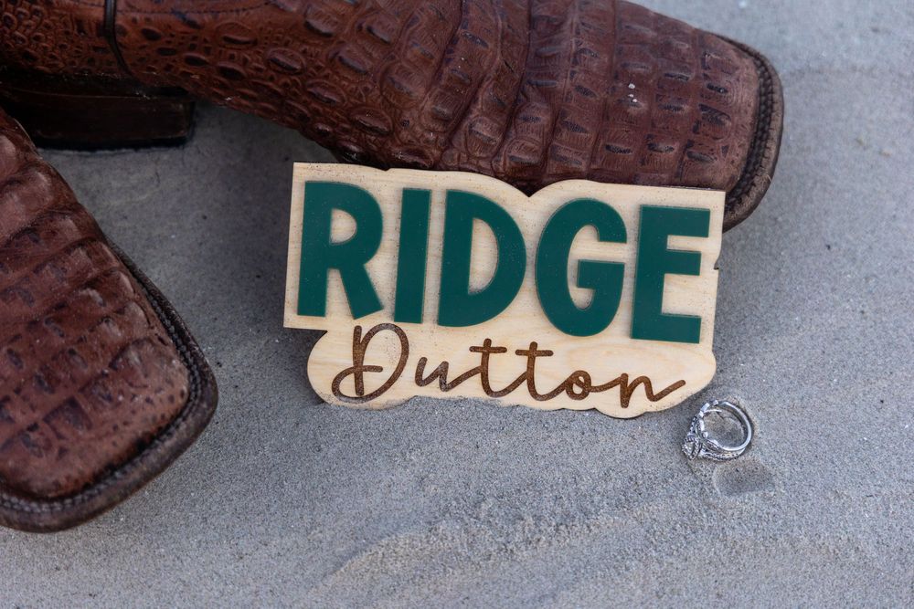 A wooden name tag or badge reading 'Ridge Dutton' with brown boots visible in the background.