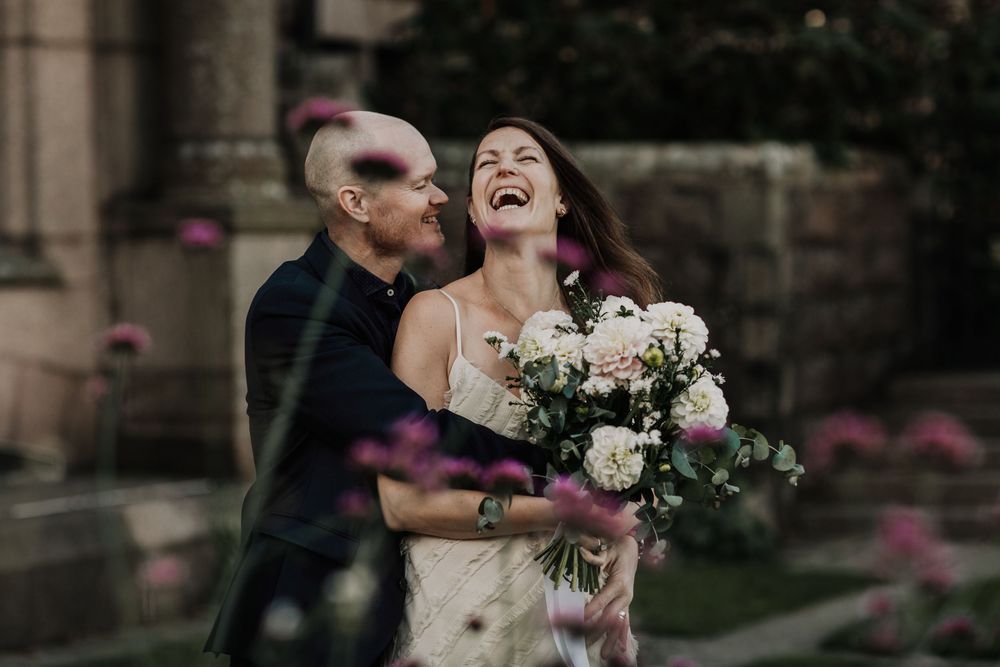 A happy couple in formal wedding attire share a romantic moment while pink bubbles float around them.