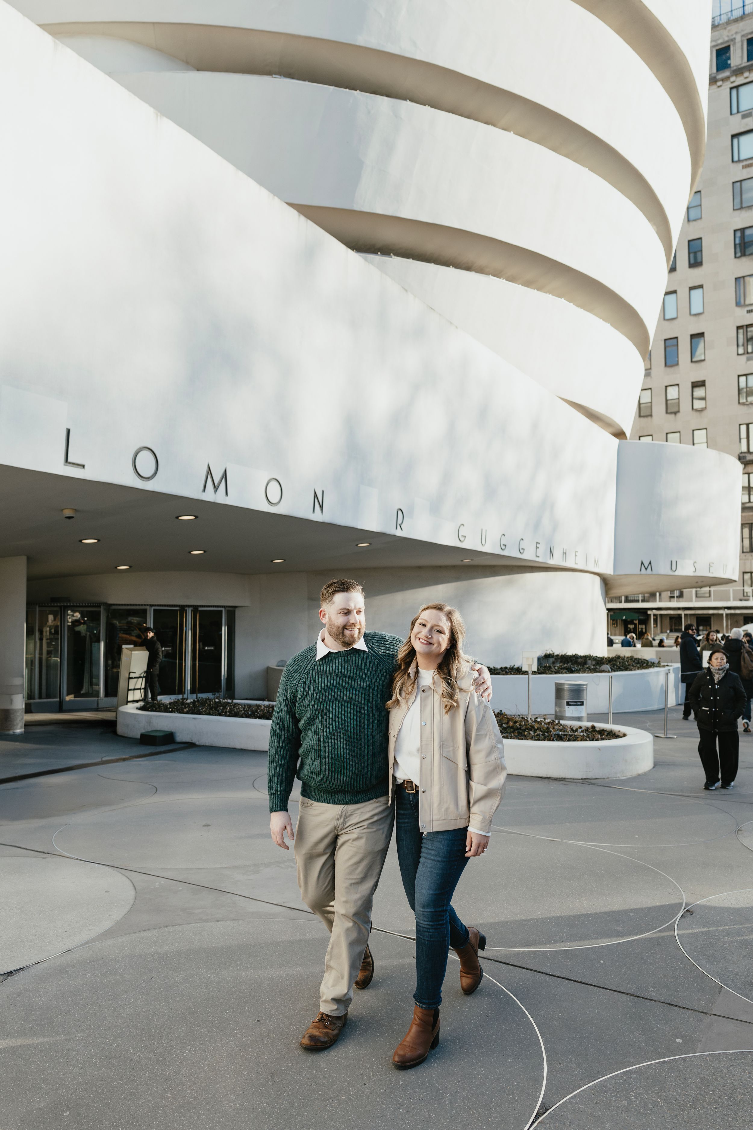 A couple poses in front of the iconic spiral architecture of the Solomon R. Guggenheim Museum in New York City - Engagement Photography