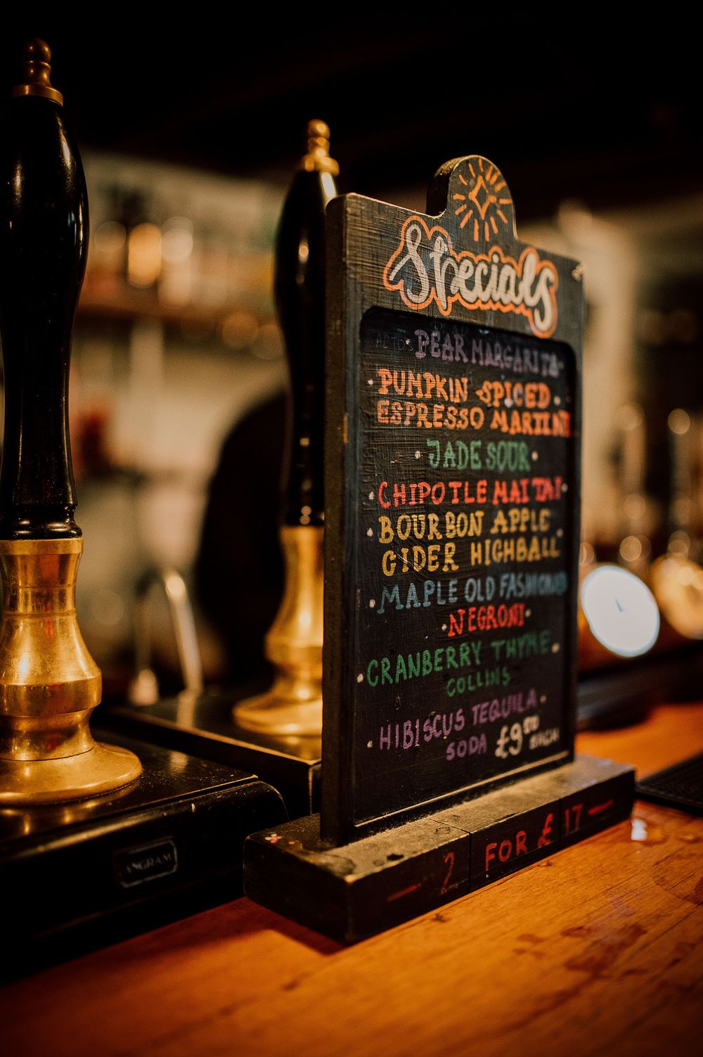 A rustic wooden bar counter with chalkboard menus and warm ambient lighting displaying coffee and drink specials.