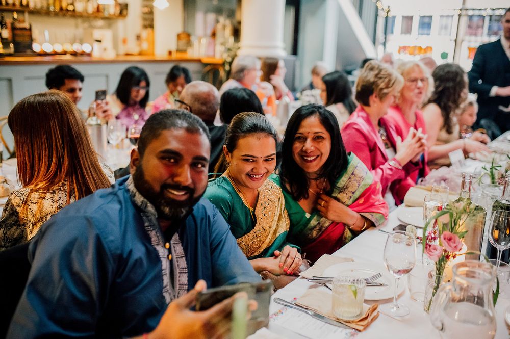 Guests enjoying a lively dinner party at a long communal table with wine glasses and festive decorations.