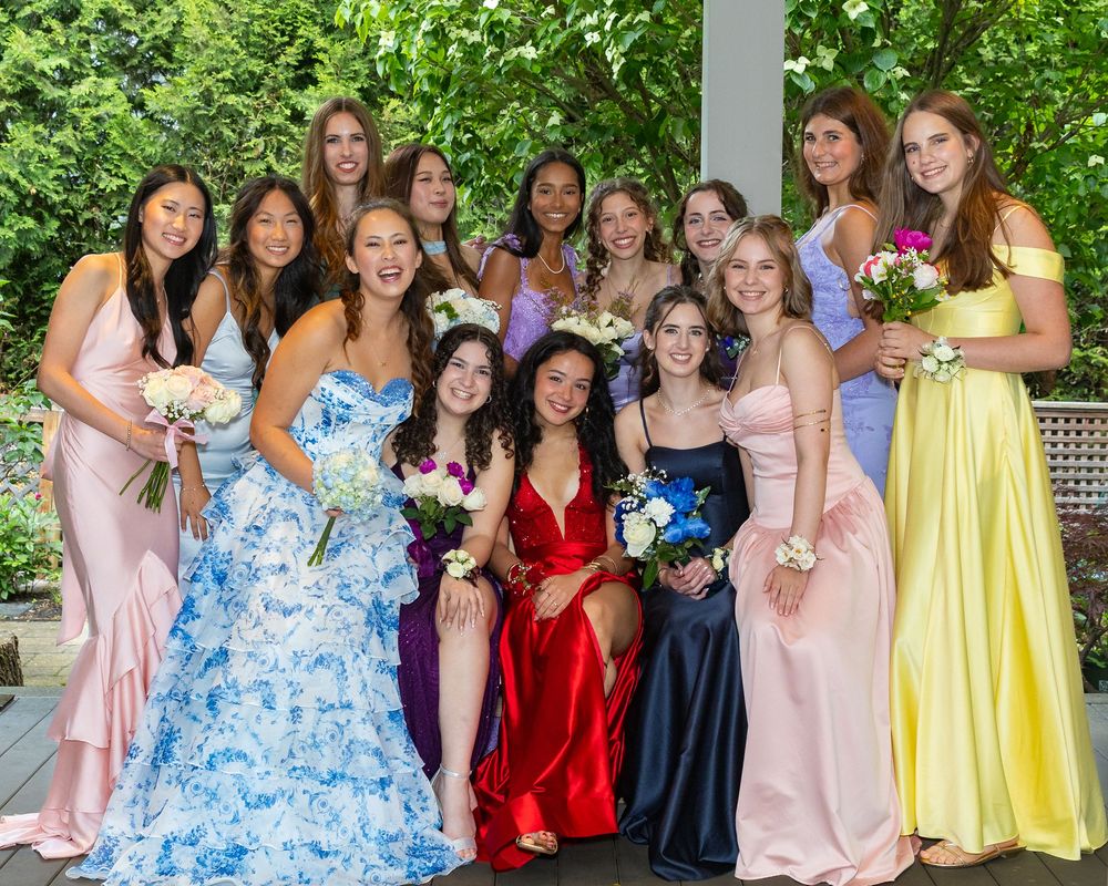 Group pose in colorful prom gowns holding bouquets, posing outdoors at a pre-prom party in Weston, MA in the Metrowest area of Boston.