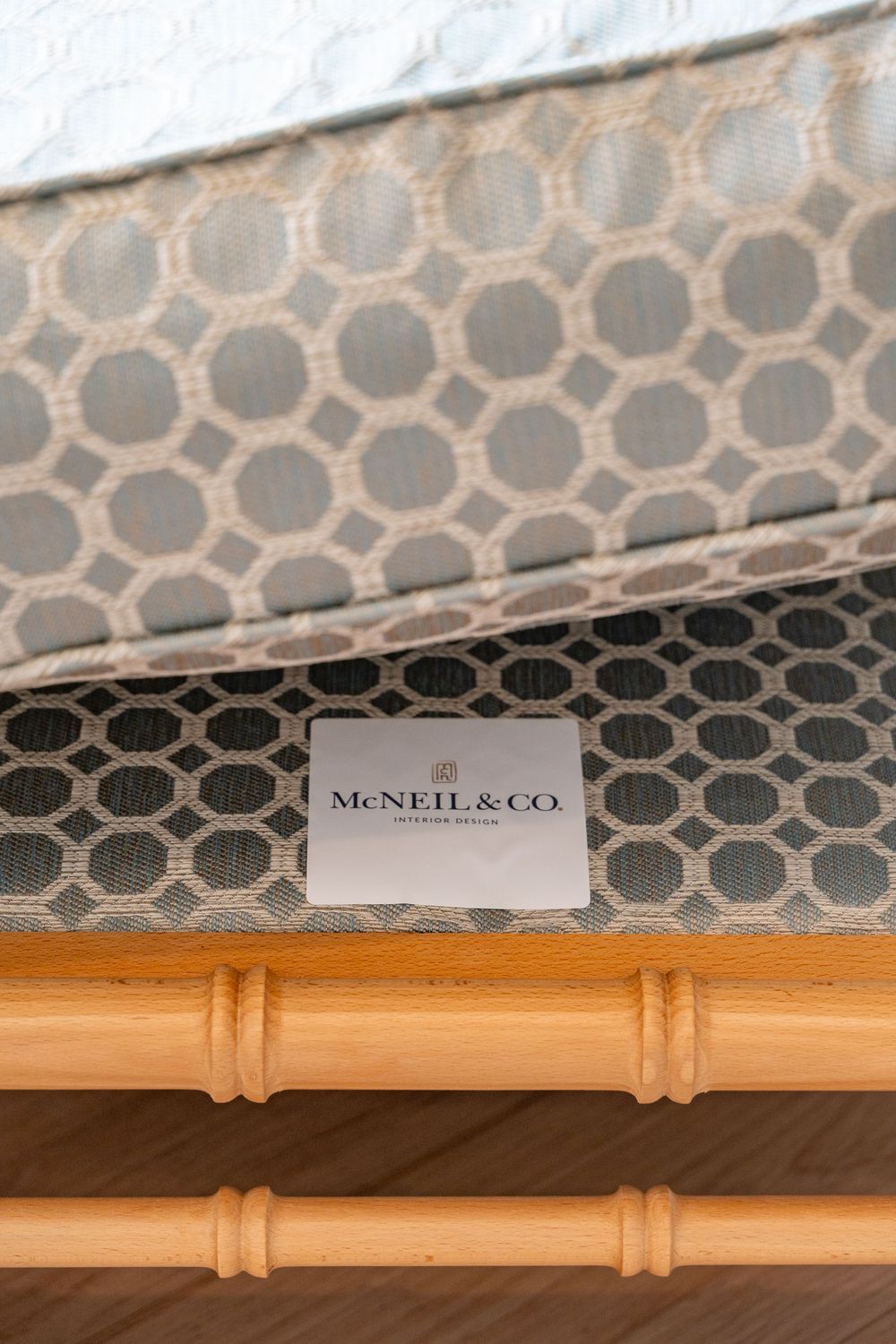 A decorative bamboo rod trim detail shown against a gray geometric patterned wallpaper with McNeil & Co branding.