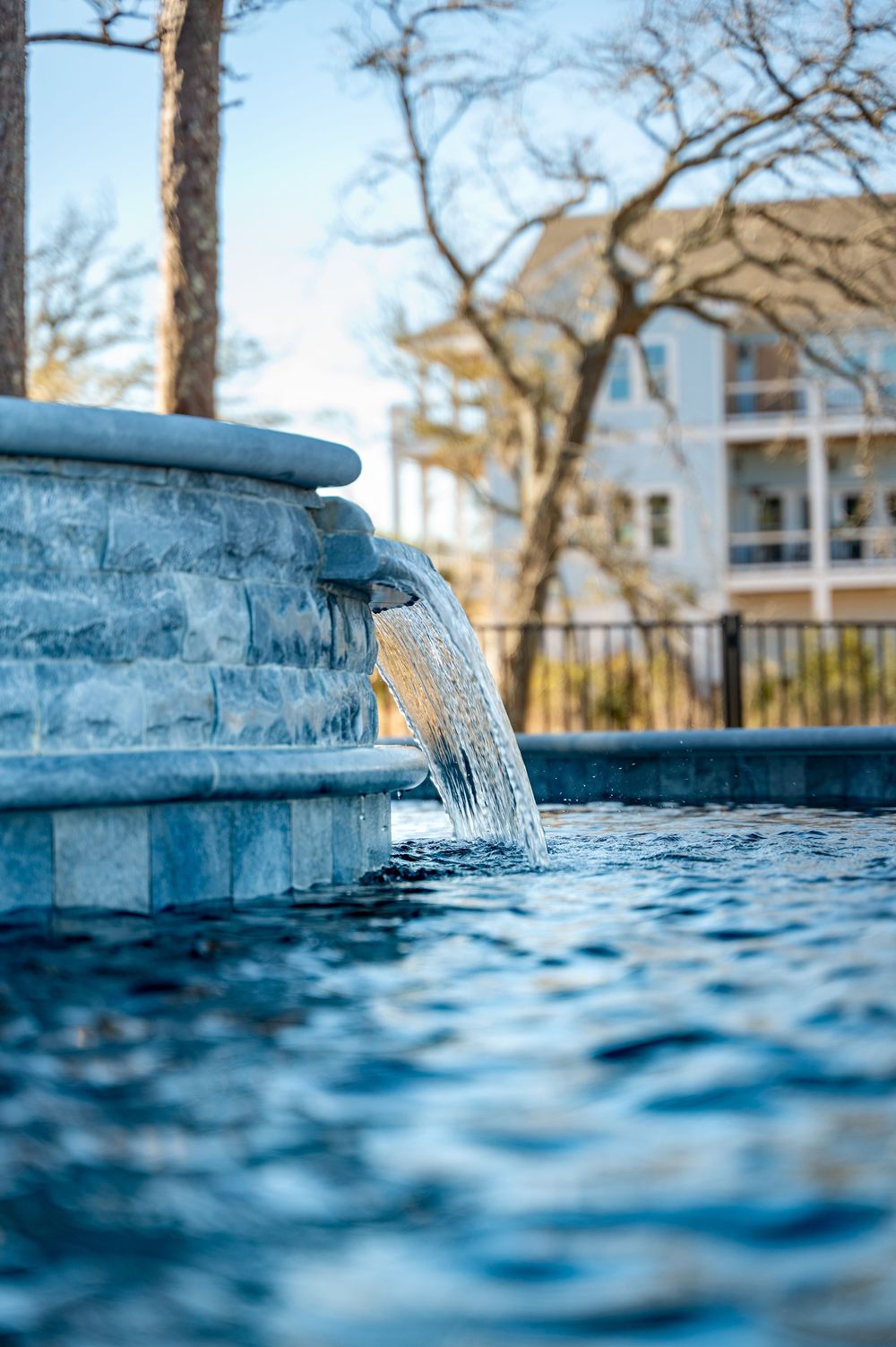 Close-up view of water cascading from a modern swimming pool's edge feature creating a serene waterfall effect.