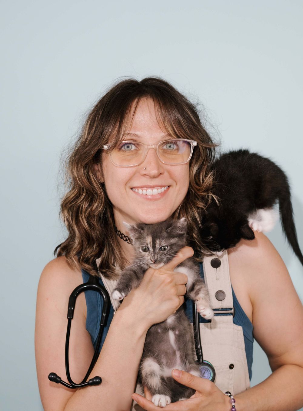 A person in a black tank top holds a gray and white kitten while smiling at the camera in a series of four photos.