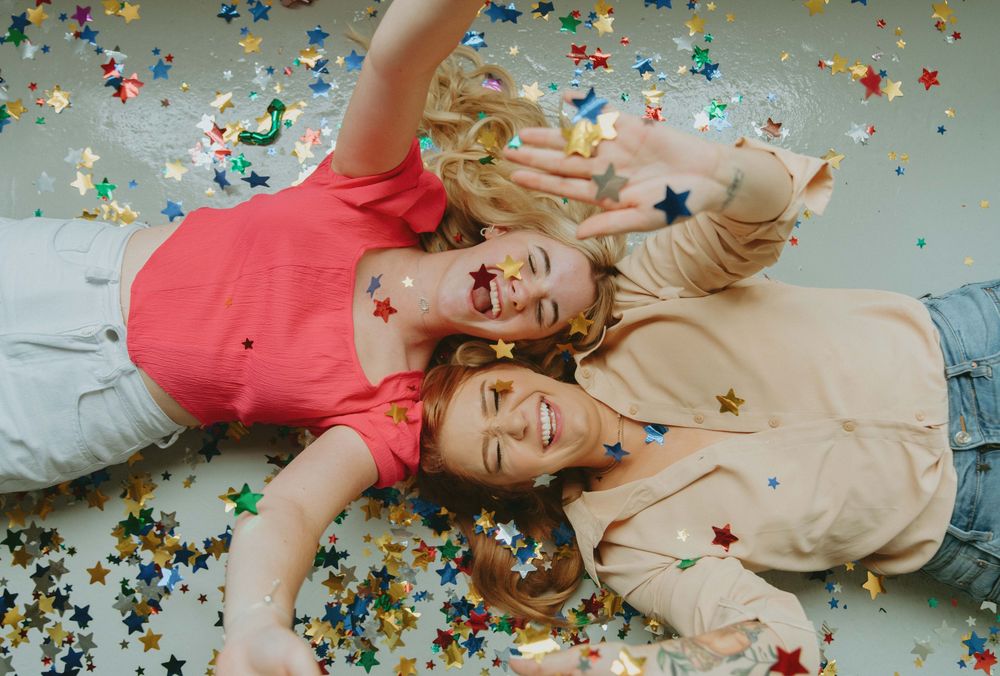 Person lying on floor with colorful confetti scattered around in celebratory scene.