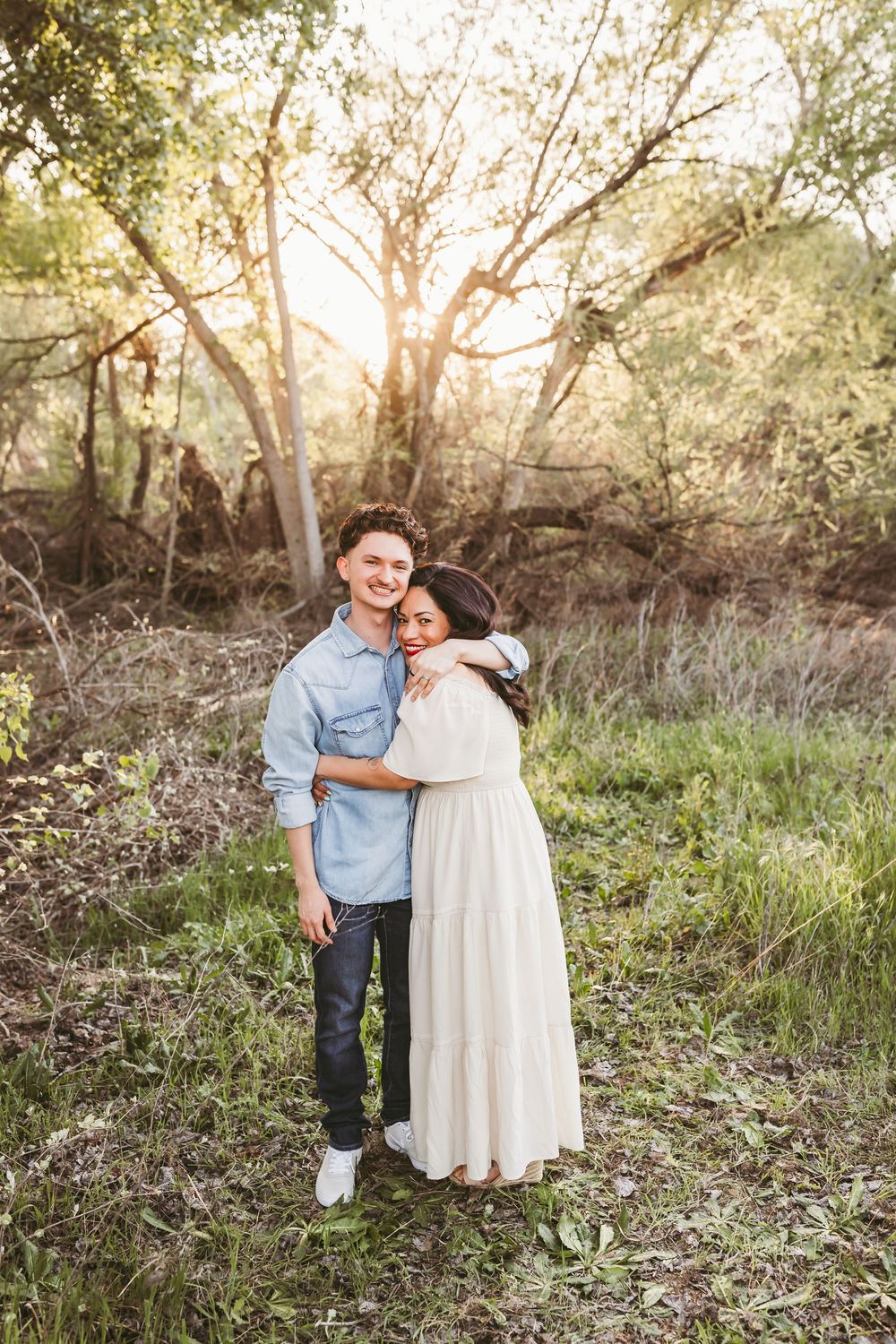 Couple sharing tender moments together during an outdoor photo session in a sunlit forest clearing.
