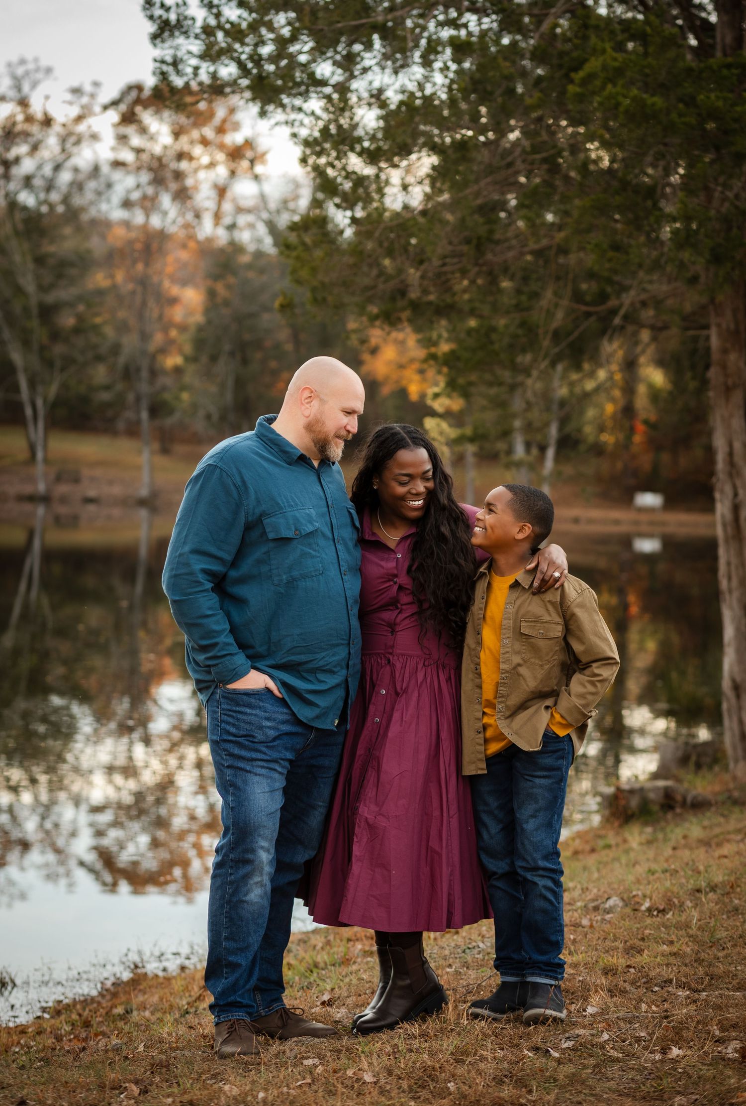Unedited image of family of three hugging against a warm fall backdrop, captured by Charlottesville baby and maternity photographer.