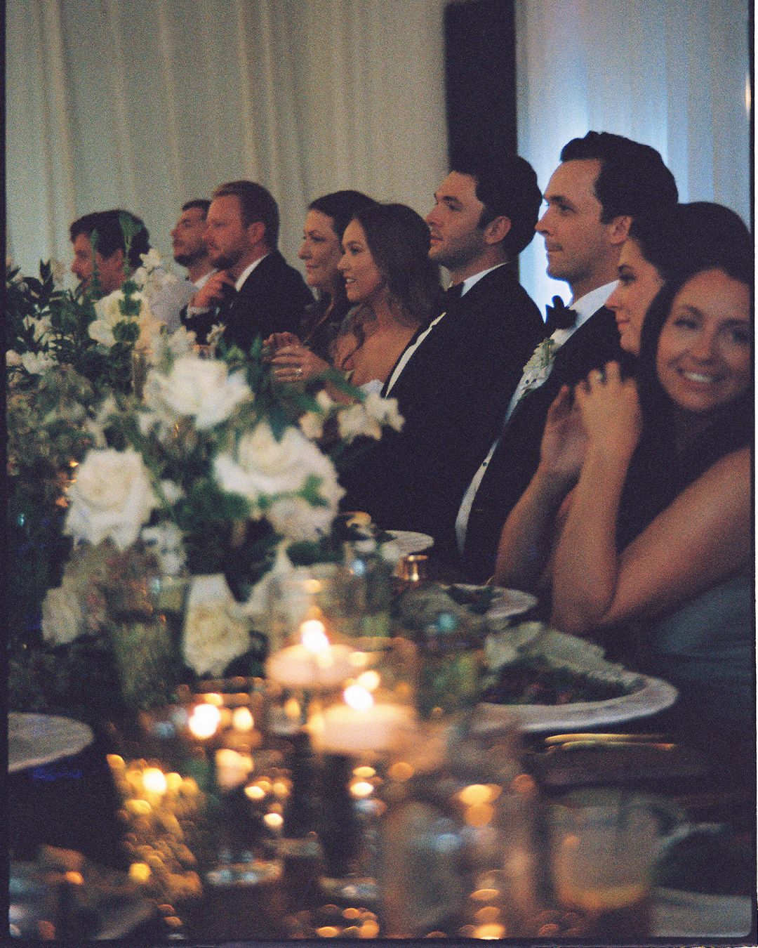 Wedding reception guests seated at candlelit tables during an elegant evening celebration.