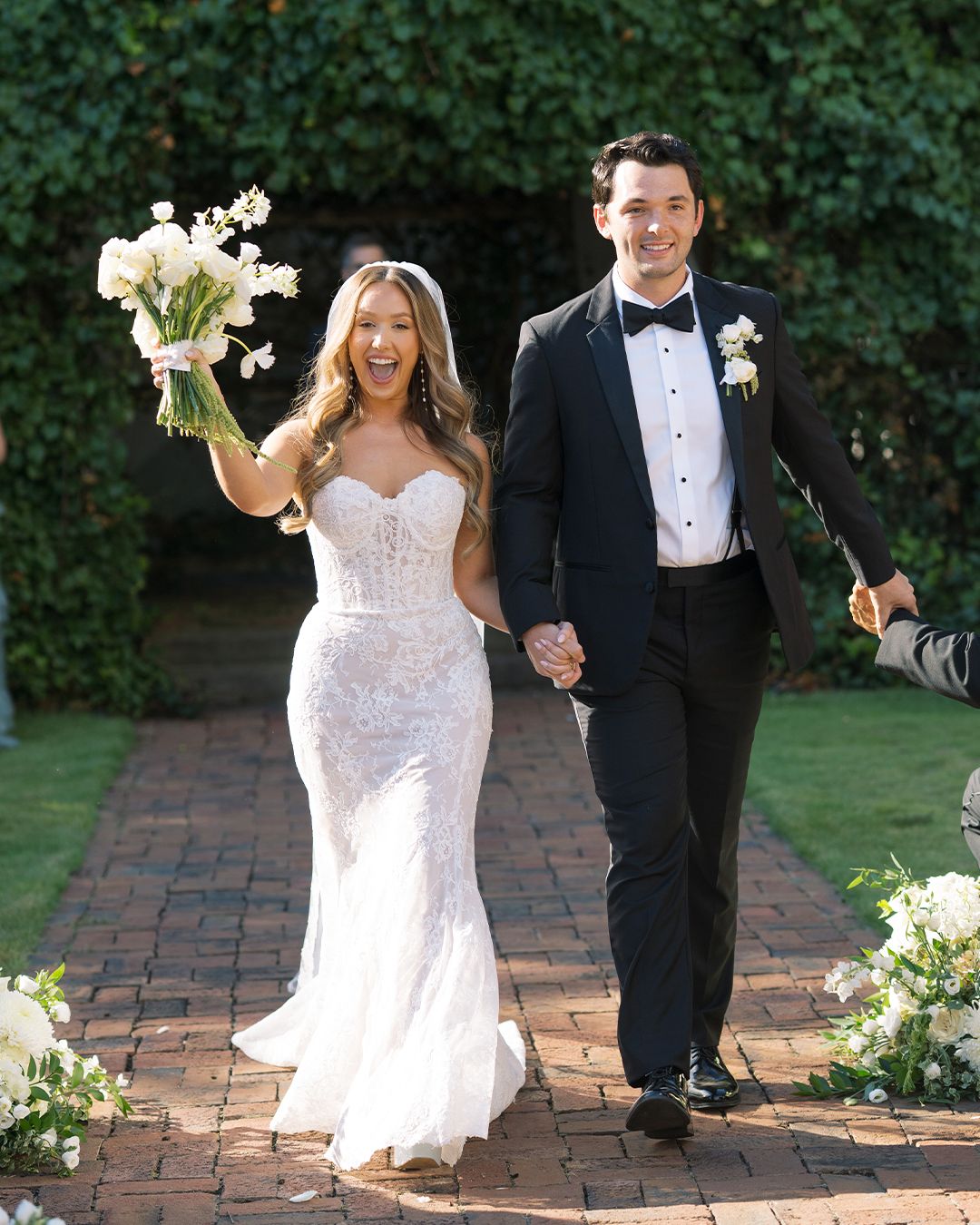 A bride and groom walking together on a brick pathway during their wedding celebration.