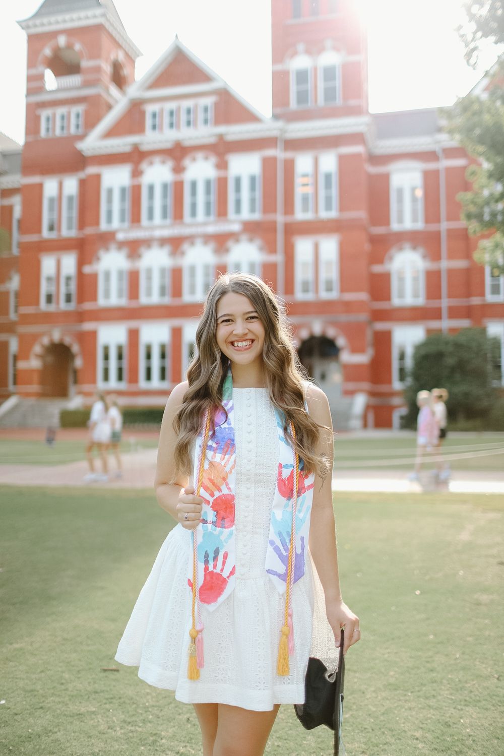 Person in colorful dress standing in front of historic red brick building.