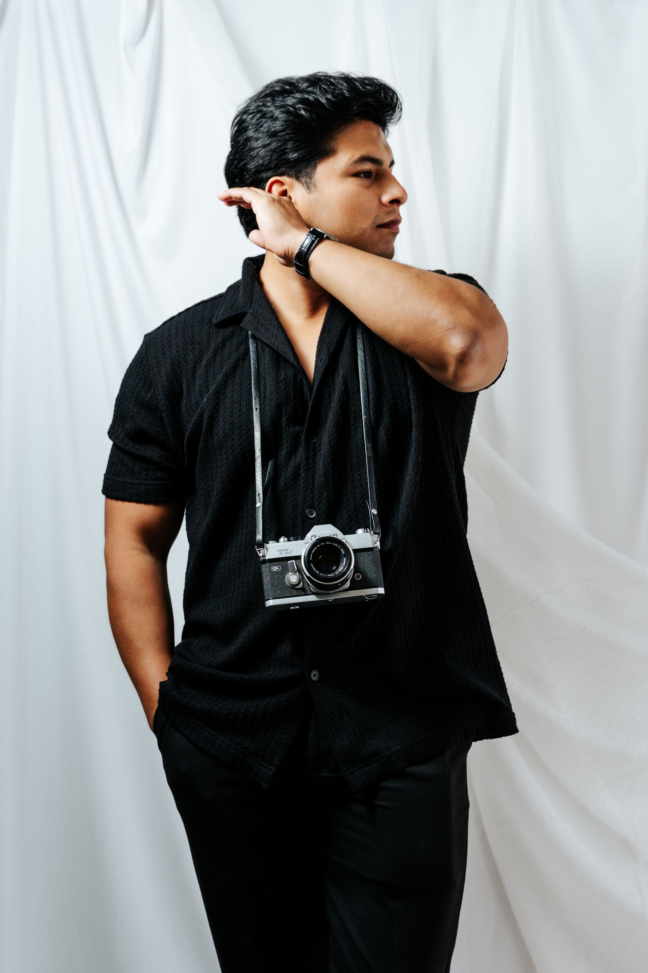 A series of black and white photos showing a person in dark clothing with a camera hanging from their neck.