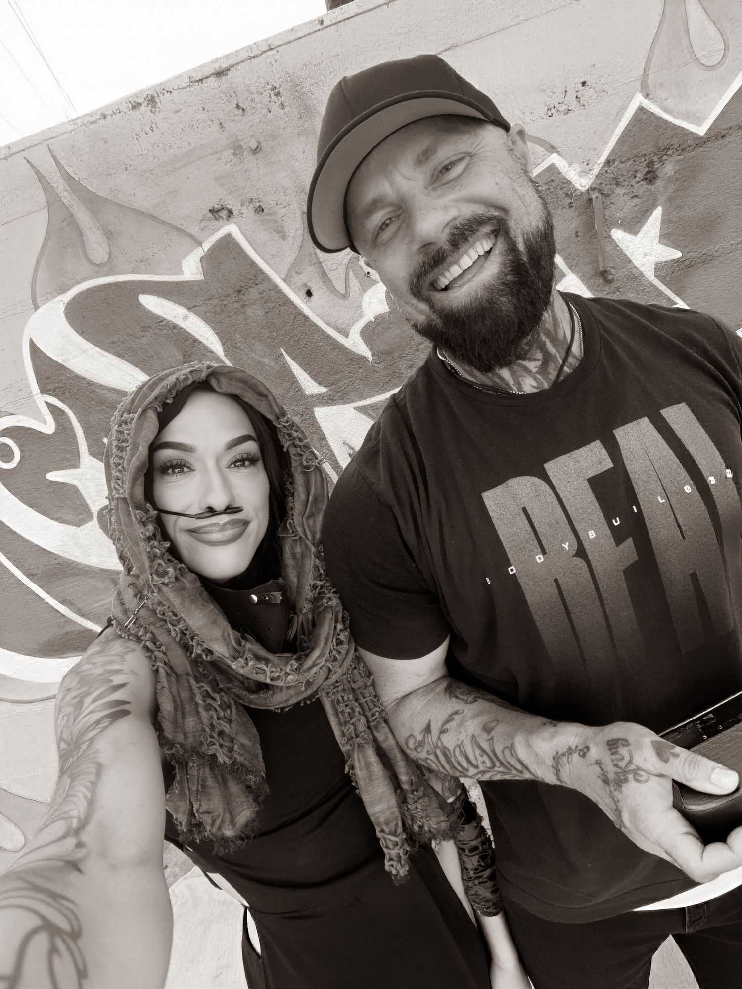 A series of black and white selfies showing a couple smiling and posing together against a wall with graffiti art.