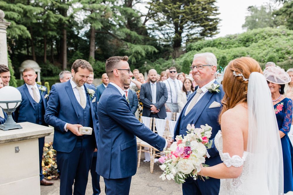 Wedding party in navy blue suits and floral bouquets gather outdoors for celebratory group photos at Italian Villa Wedding