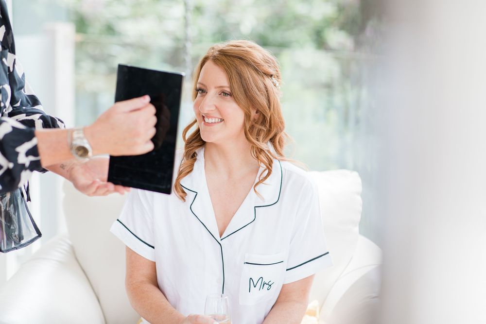Bride getting ready in white robe with monogram during morning wedding preparations by Maddie Waters Photography