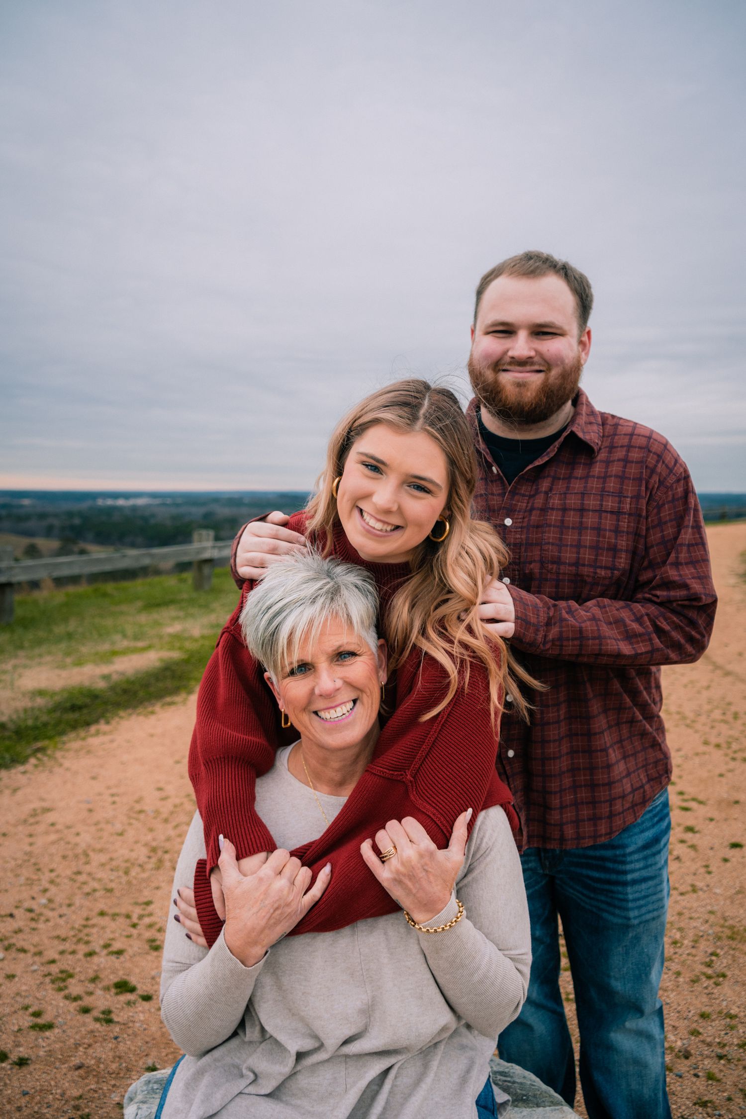 Three people enjoying a candid moment together outdoors on a hilltop.