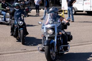 Two motorcyclists riding large touring bikes in a parking lot.