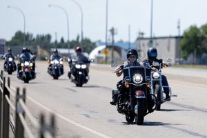 Motorcycles riding in formation on a highway during a group ride or parade.
